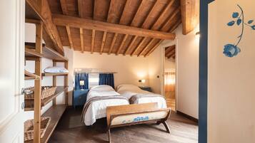 Ein gemütliches Schlafzimmer mit Holzbalken, einem Etagenbett, einem Nachttisch mit Lampe und einer Wand mit floralem Dekor.