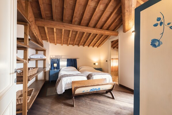 Un dormitorio acogedor con vigas de madera, una litera, una mesita de noche con lámpara y un muro con diseño floral.
