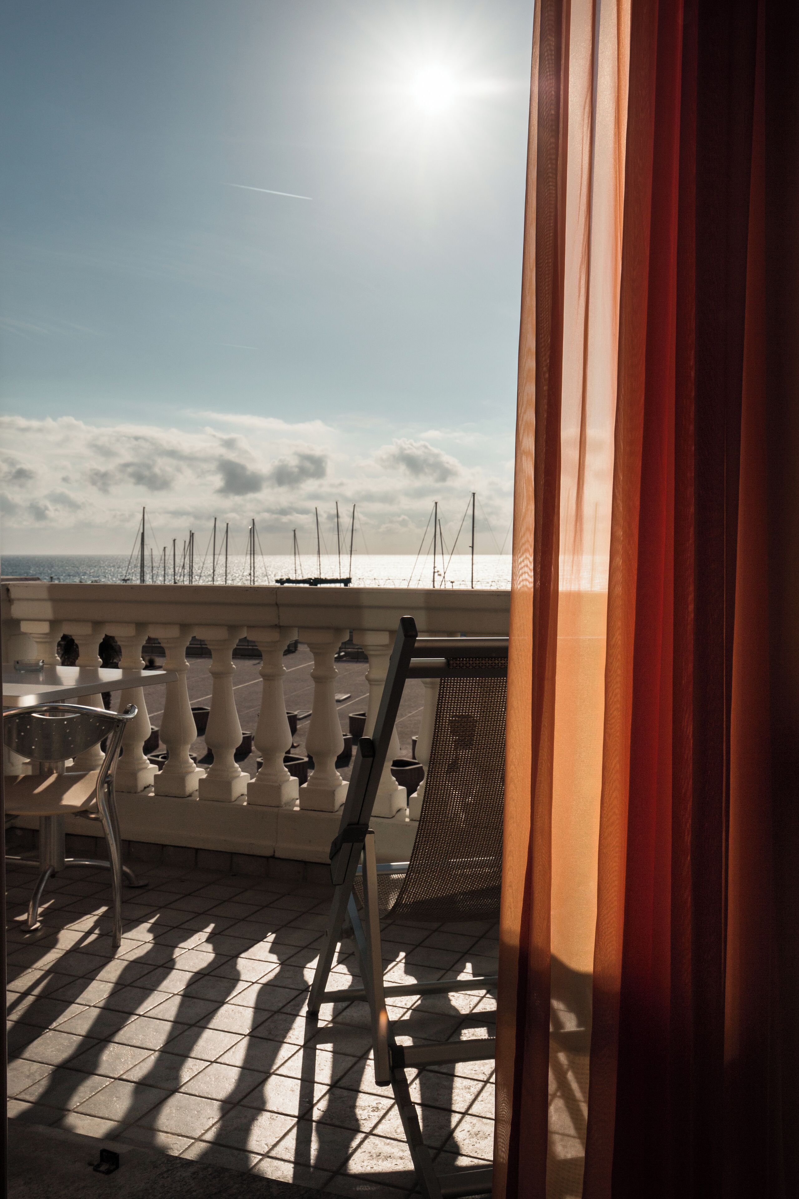 Un balcón con vista al mar, una silla y una mesa.