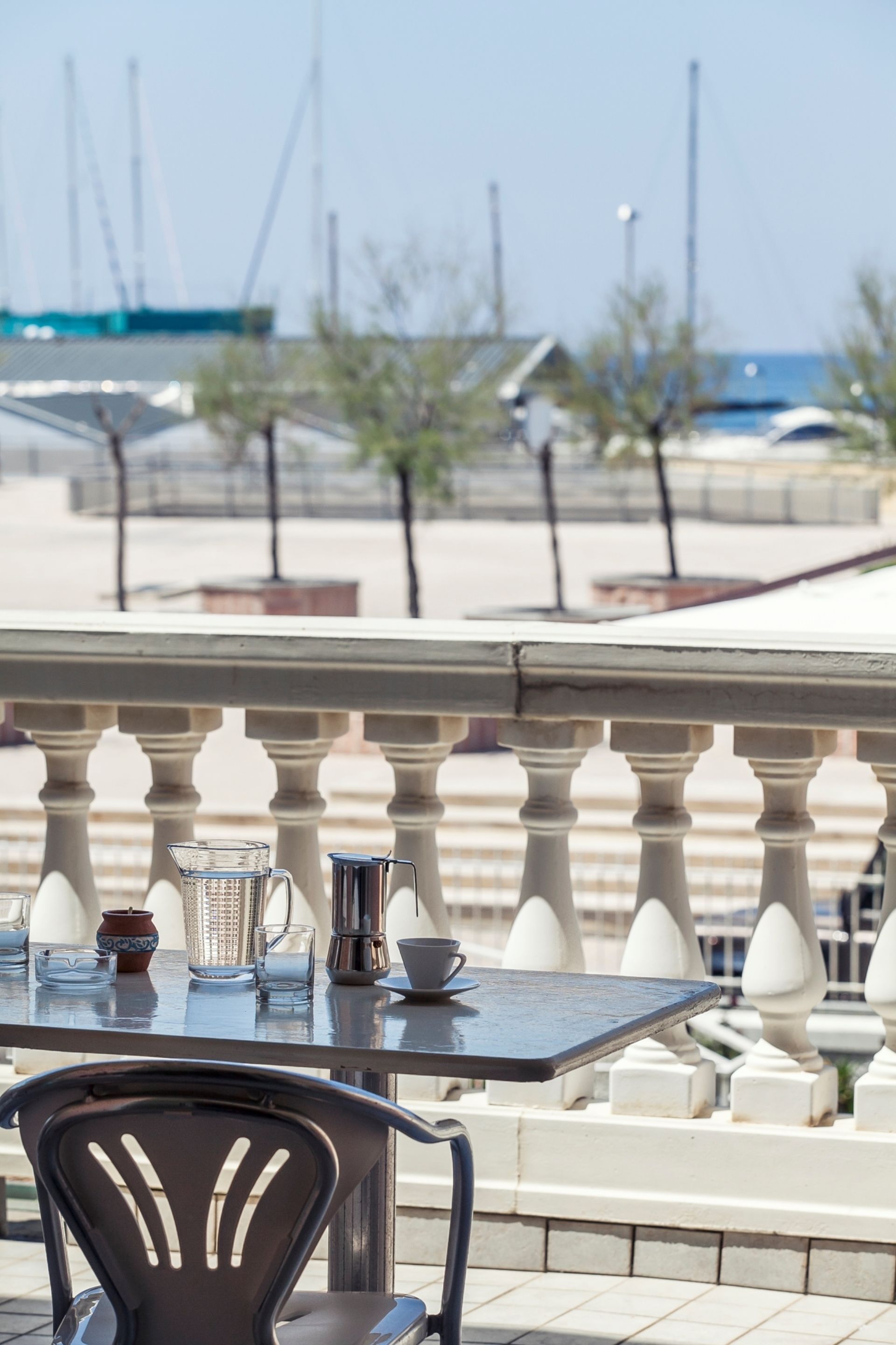 A balcony with a table and chairs, overlooking a marina with boats.
