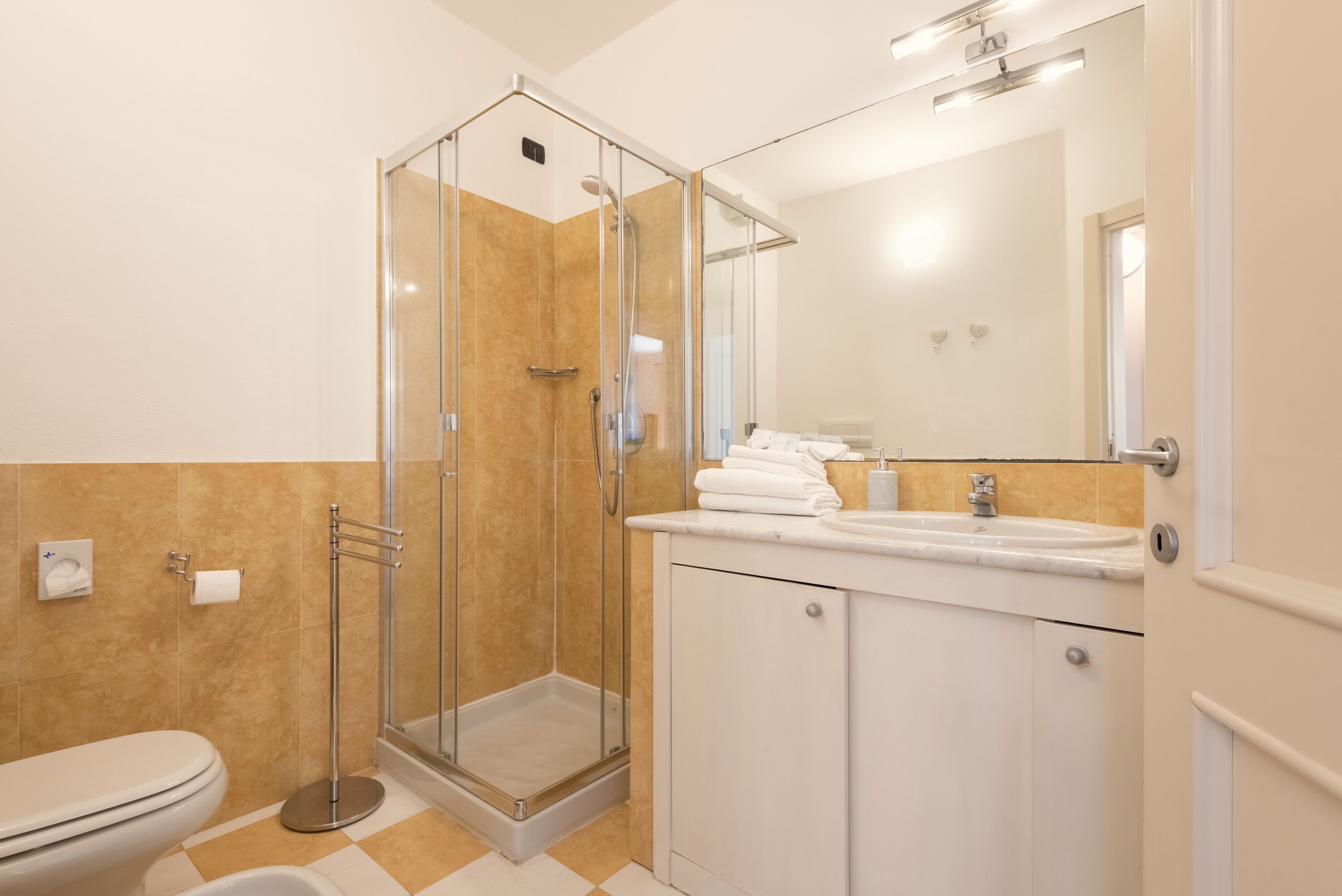 Une salle de bain moderne avec une douche à parois de verre, des toilettes et un lavabo avec un miroir.
