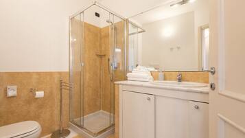 Une salle de bain moderne avec une douche à parois de verre, des toilettes et un lavabo avec un miroir.