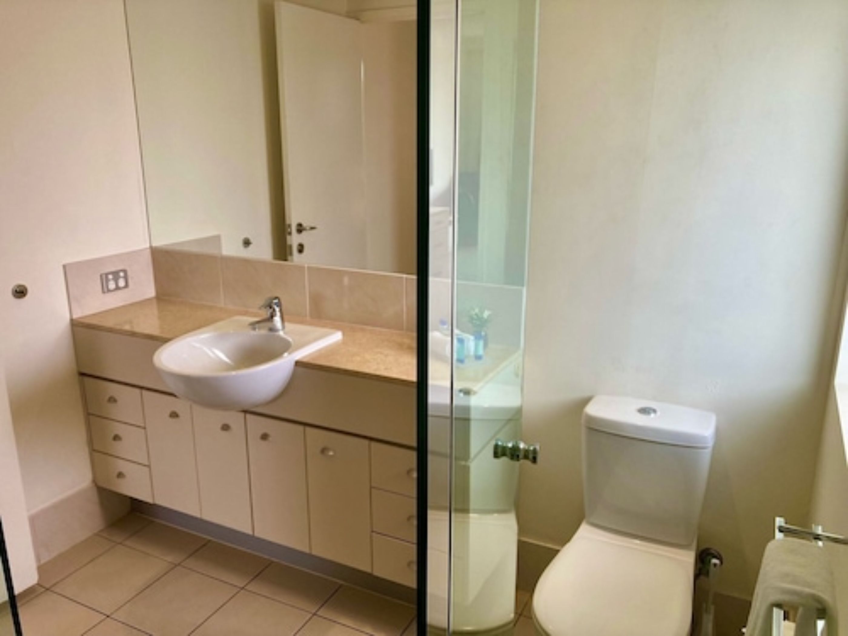 Une salle de bain avec un lavabo blanc, des meubles de couleur beige et des toilettes.