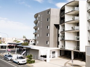 A modern multi-story building with balconies, a restaurant, and a parking area. - Ocean Views Resort (Caloundra)
