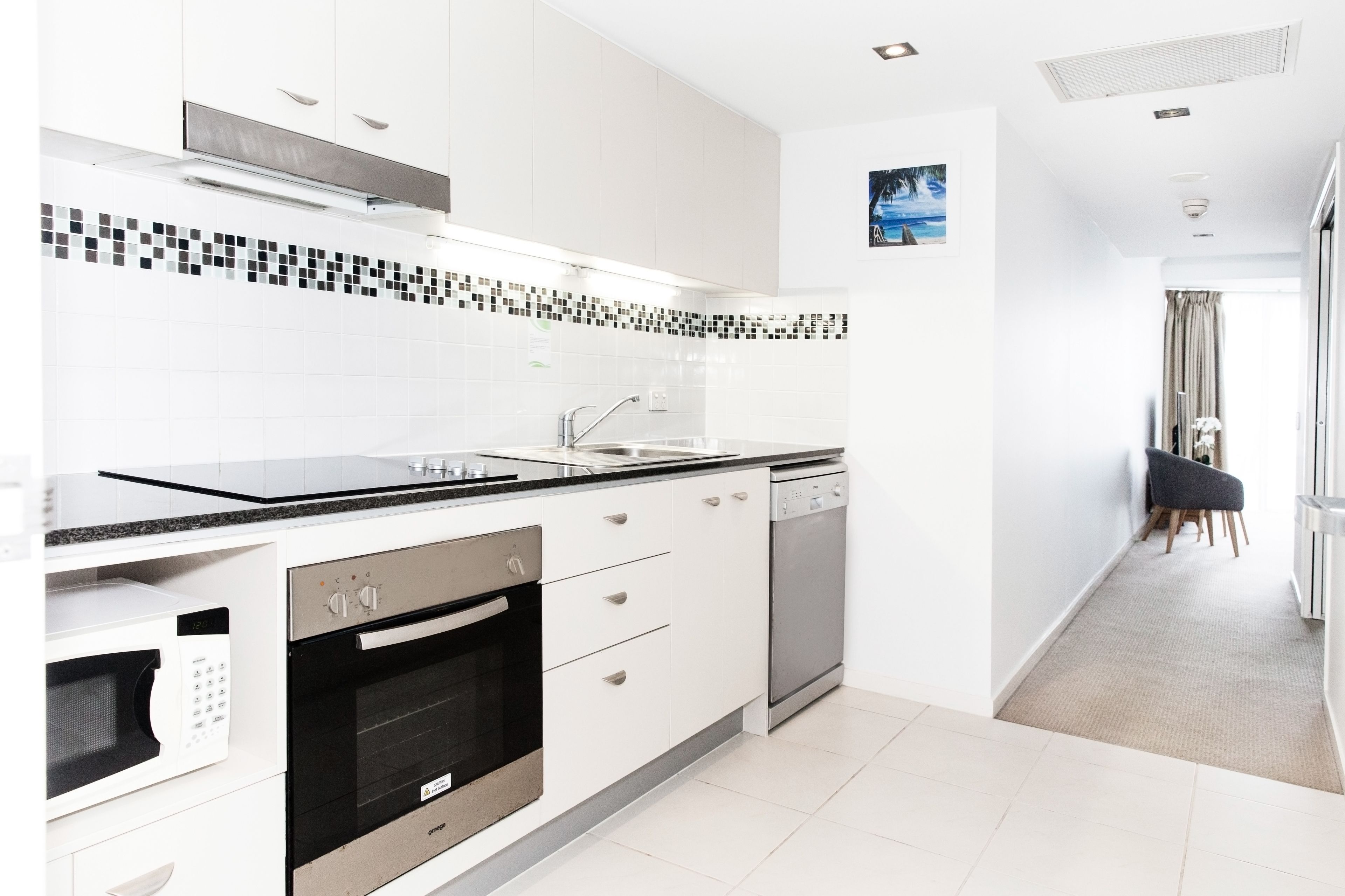 A modern kitchen with white cabinets, a black countertop, and a dishwasher.