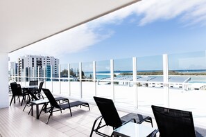 A modern hotel room with large windows offering a view of the beach and buildings. - Ocean Views Resort (Caloundra)