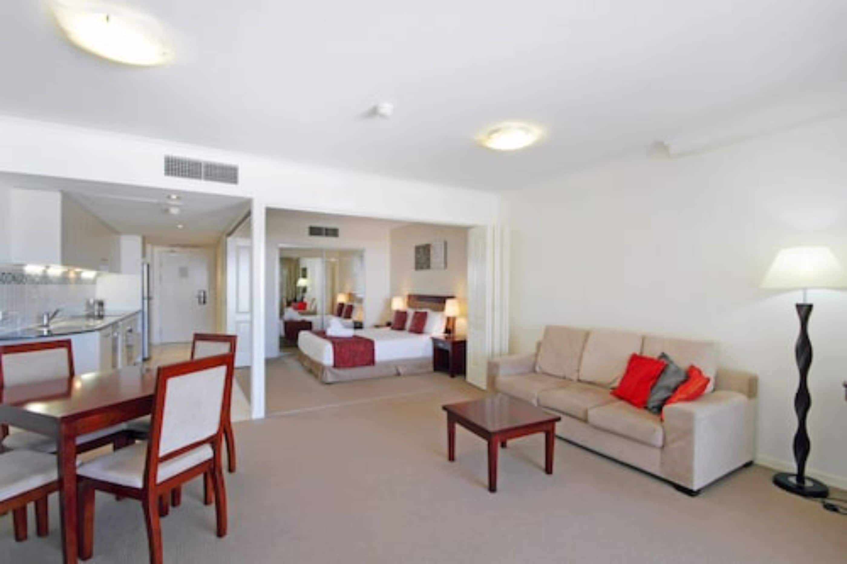 A hotel room with a dining area, a sofa, and a lamp.