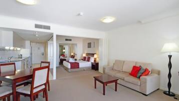 A hotel room with a dining area, a sofa, and a lamp.