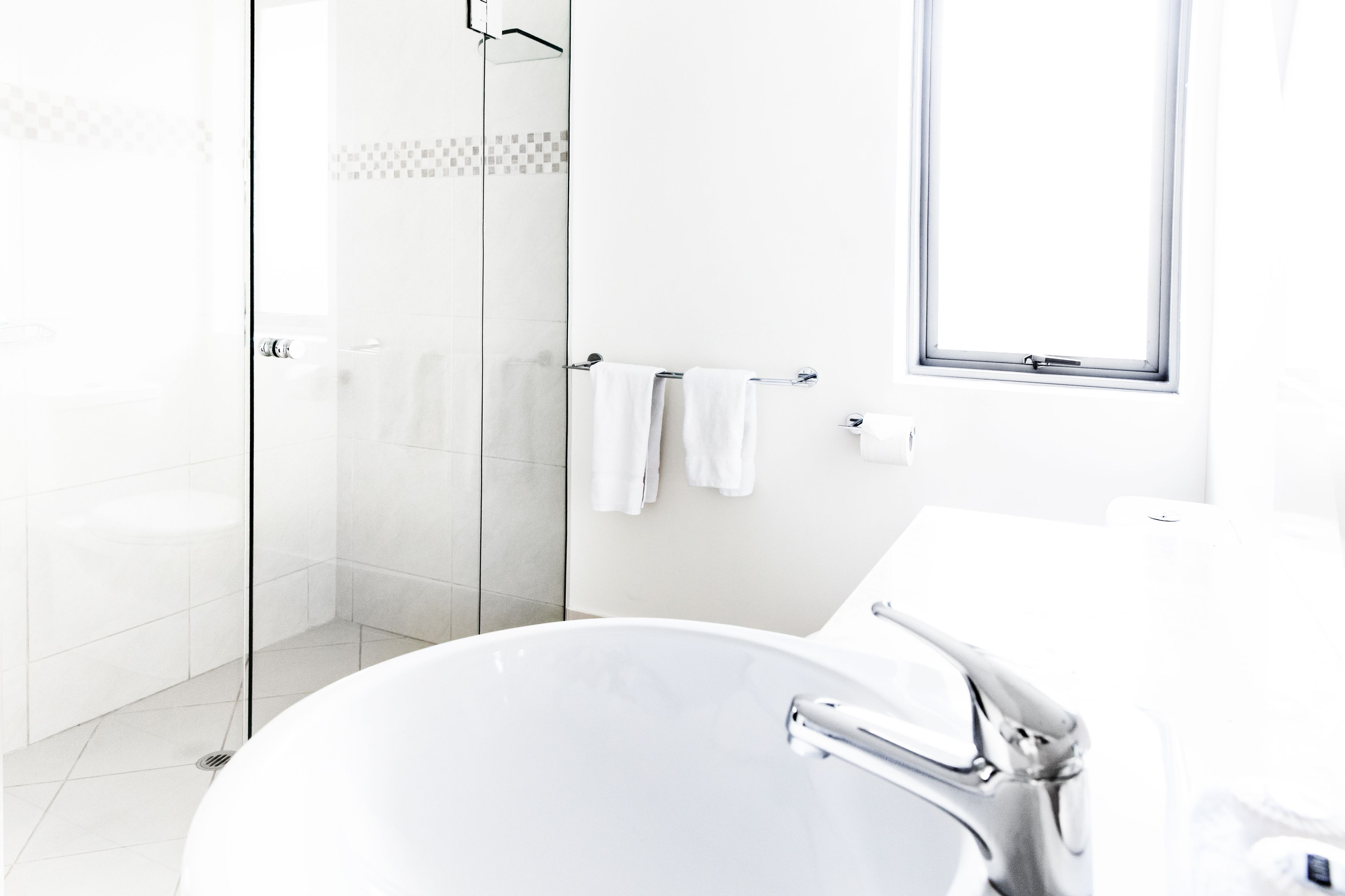 Un baño moderno con una bañera independiente, un box de ducha de vidrio y un ventanal que proporciona luz natural.