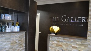 Ein Empfangsbereich mit einer Steinwand und einem Schild mit der Aufschrift 'The Gallery Apartments & Villas'.