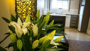 Eine moderne Küche mit Kochinsel, einem Essbereich mit schwarzem Sofa und einer dekorativen Vase mit weißen Blumen.