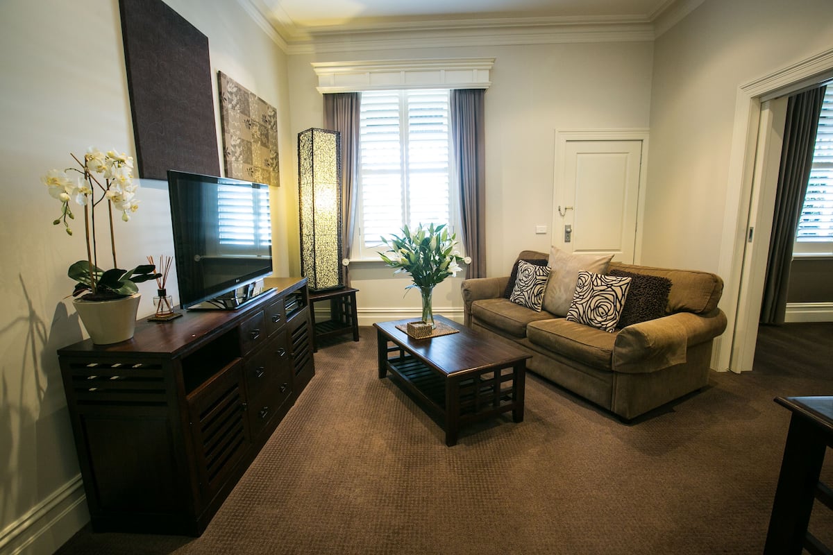 Una sala de estar con sofá, mesa de centro, televisor y plantas decorativas.