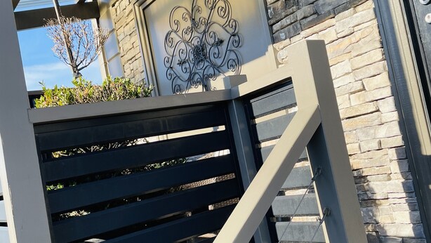 Eine moderne Außentreppe mit Metallgeländern und einer Wand aus Stein im Hintergrund.