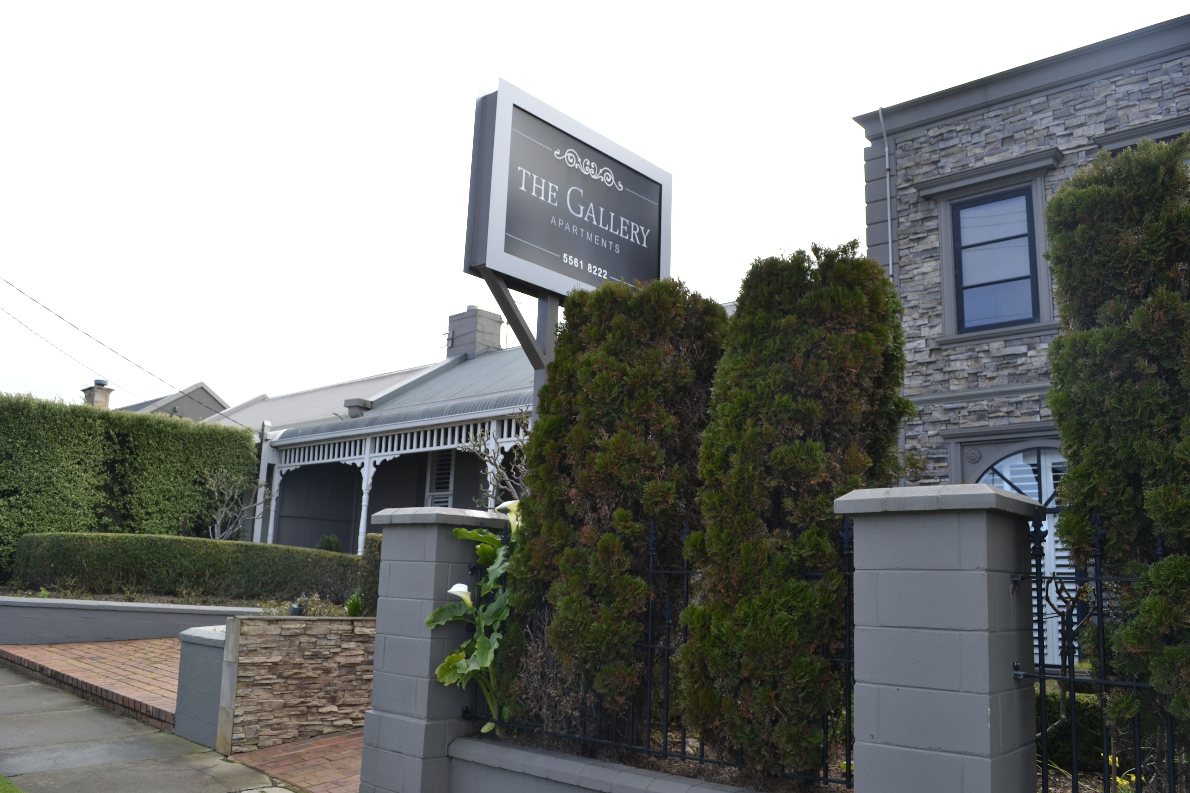 A sign for The Gallery Apartments with a stone facade and a gated entrance.