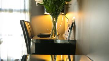A dining table with a vase of white flowers, a lamp, and a magazine holder.