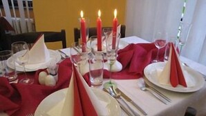 A table set for a meal with red napkins, white plates, and candles.