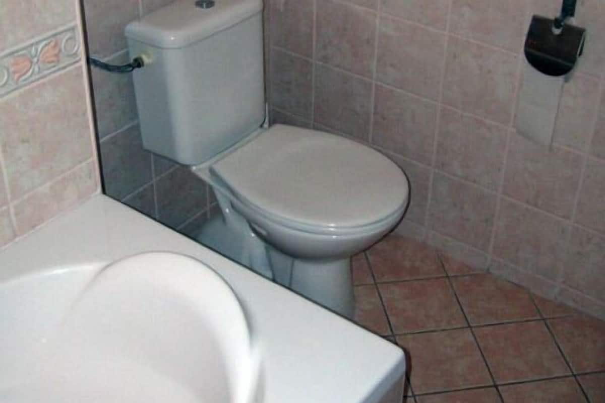 A bathroom with a toilet, a sink, and a trash bin.
