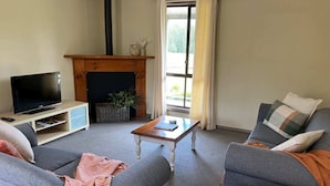 Un salon avec un téléviseur, un canapé, une table basse et une cheminée.