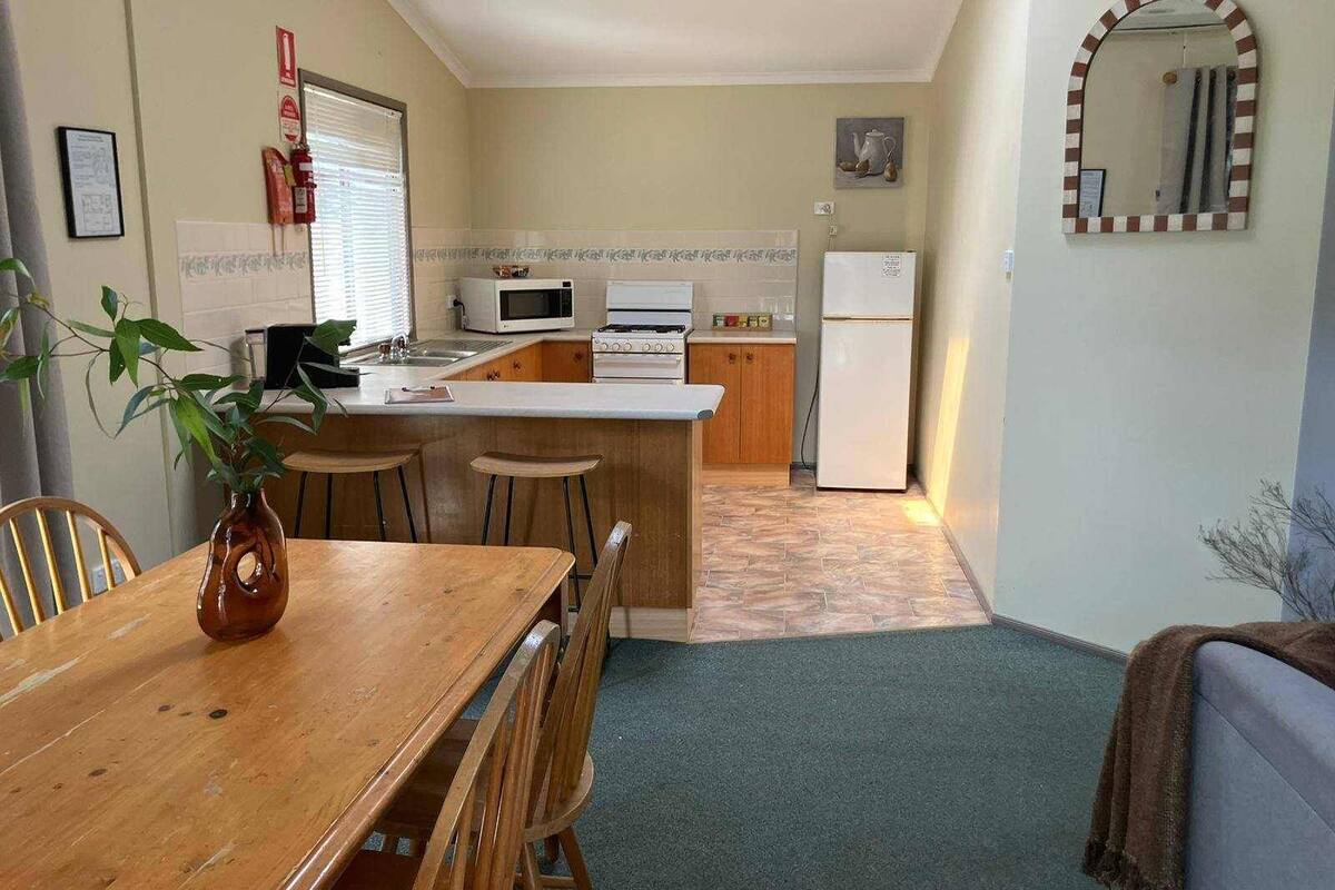 Una cocina compacta con comedor, microondas, estufa y refrigerador.