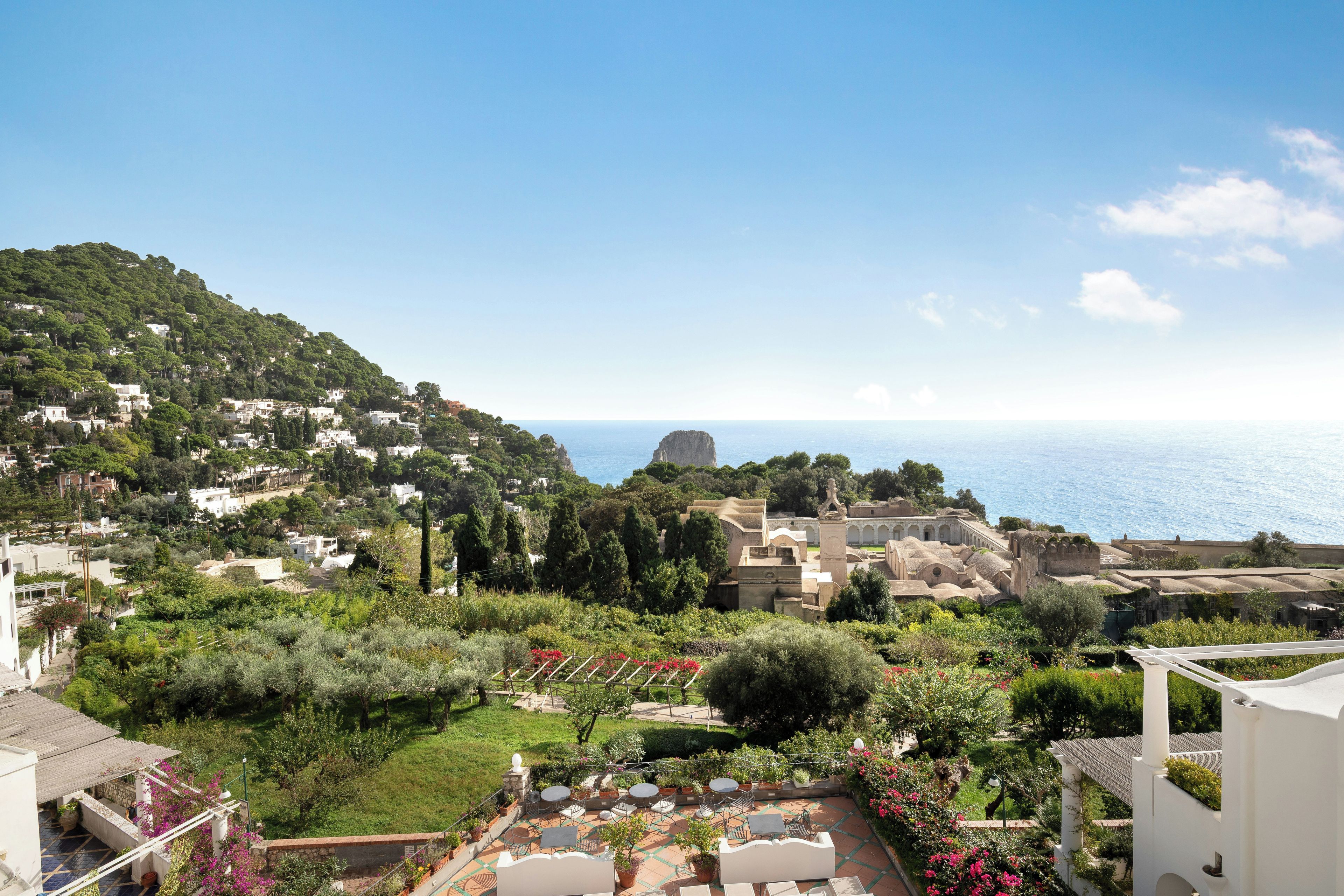 Un pueblo costero con casas escalonadas, un jardín con plantas en macetas y vistas al mar.