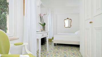 Une chambre avec un lit, un bureau doté d’un miroir, une chaise et une fenêtre avec des rideaux.
