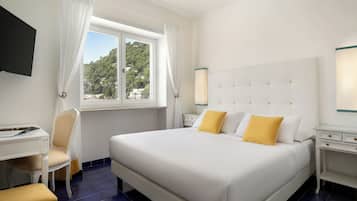 Een hotelkamer met een bed, een bureau, een stoel, een televisie en een raam met gordijnen.