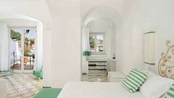 A bedroom with a bed, a desk, and a view of the outside.