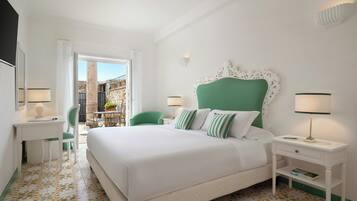 A hotel room with a bed, a desk, a chair, a nightstand, and a view of a building outside.