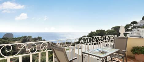 Un balcon avec une table, des chaises et une vue sur la mer.