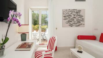 Una sala de estar moderna con un sofá, una silla, una mesita, un televisor y una puerta que da a un espacio exterior.