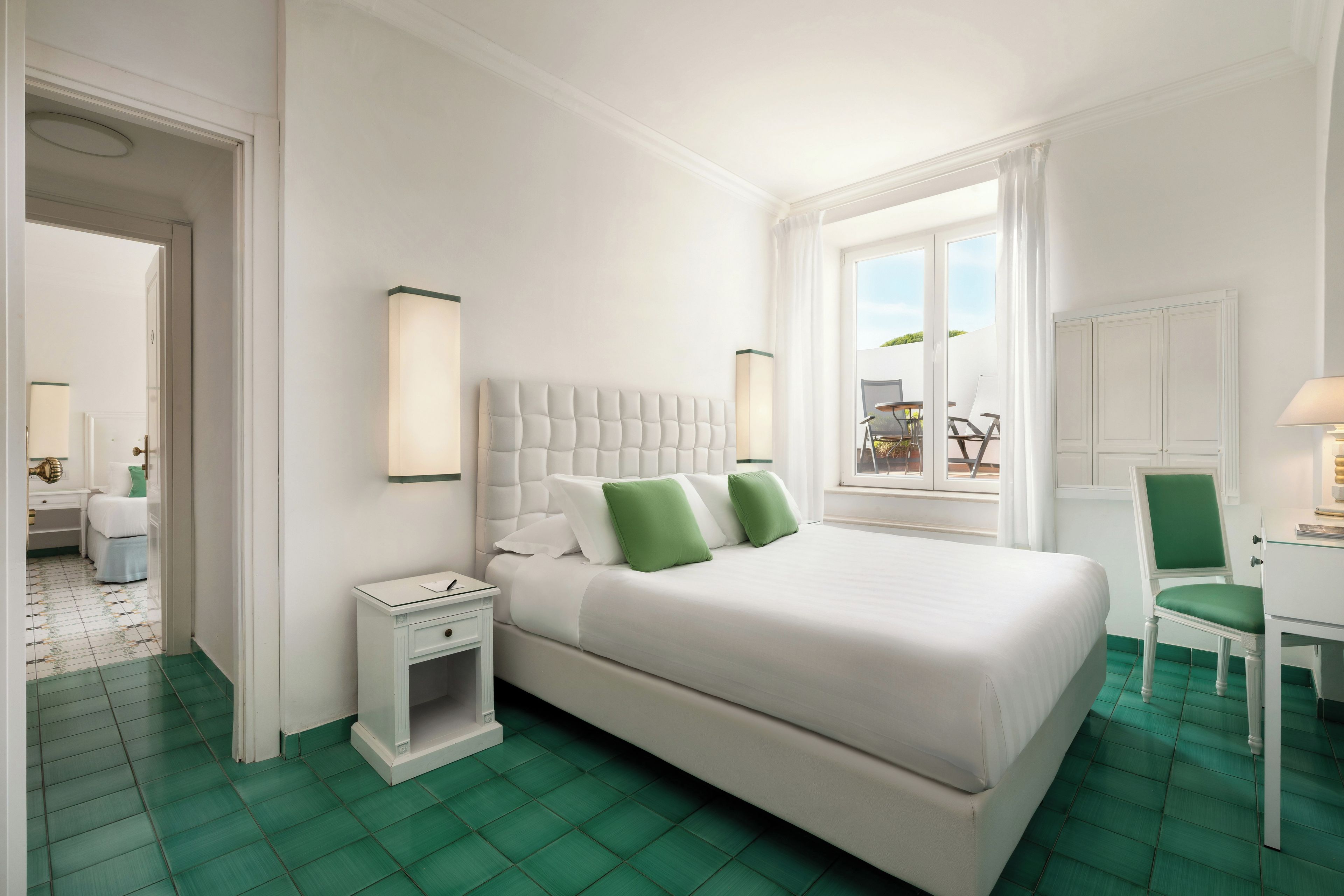 Habitación de hotel con una cama grande, un escritorio, una silla, una mesita de noche y una ventana con vistas.