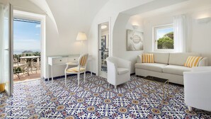 Una habitación con un sofá blanco, una silla, un escritorio y un suelo con estampado.