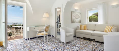 A room with a white sofa, a chair, a desk, and a patterned floor.