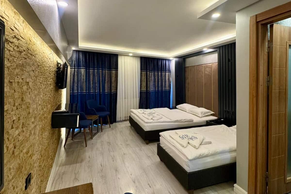 A hotel room with two beds, a desk, and a chair.