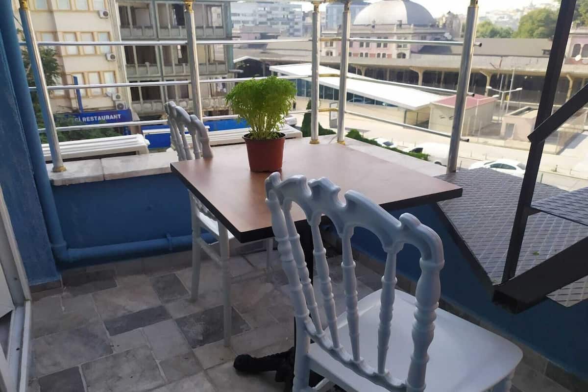 A balcony with a table, chairs, and a potted plant.
