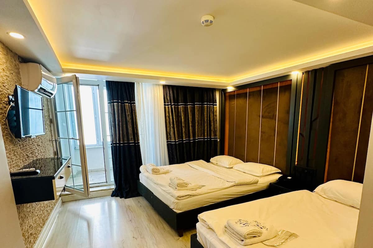 A hotel room with two beds, a TV, and a sliding glass door to the outside.