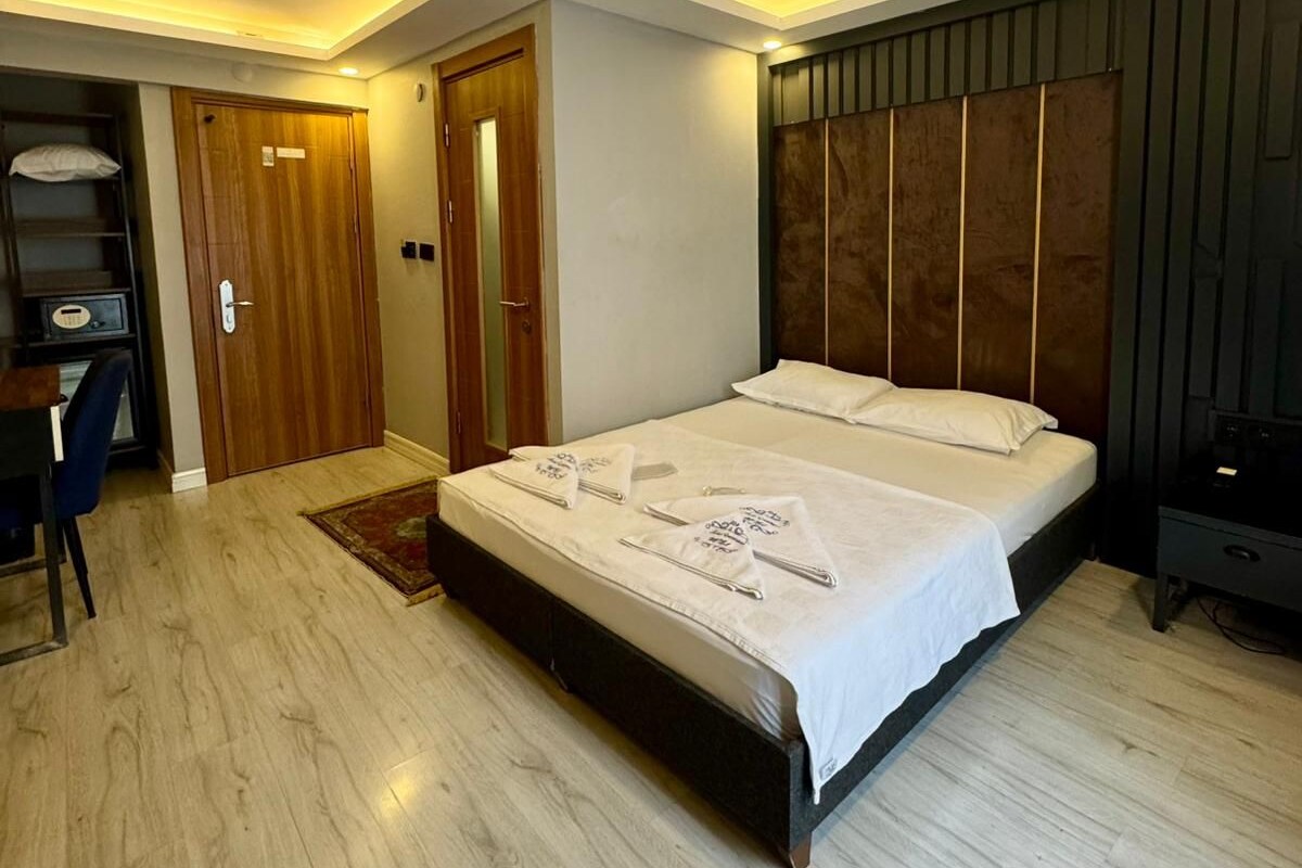 A bedroom with a bed, a desk, and a wardrobe.