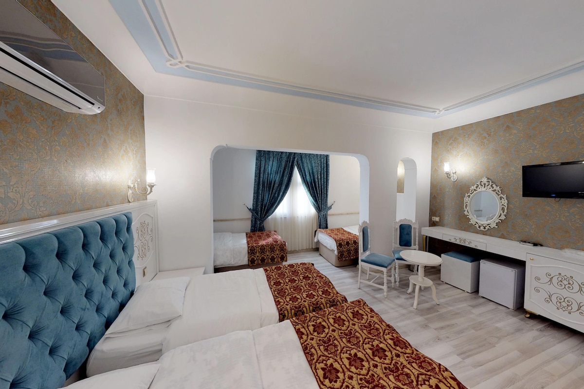 A hotel room with a large bed, a desk, a chair, a TV, and a mirror.