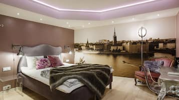 Quarto com mural da paisagem urbana, cama com manta de pele, escrivaninha com luminária e uma cadeira.