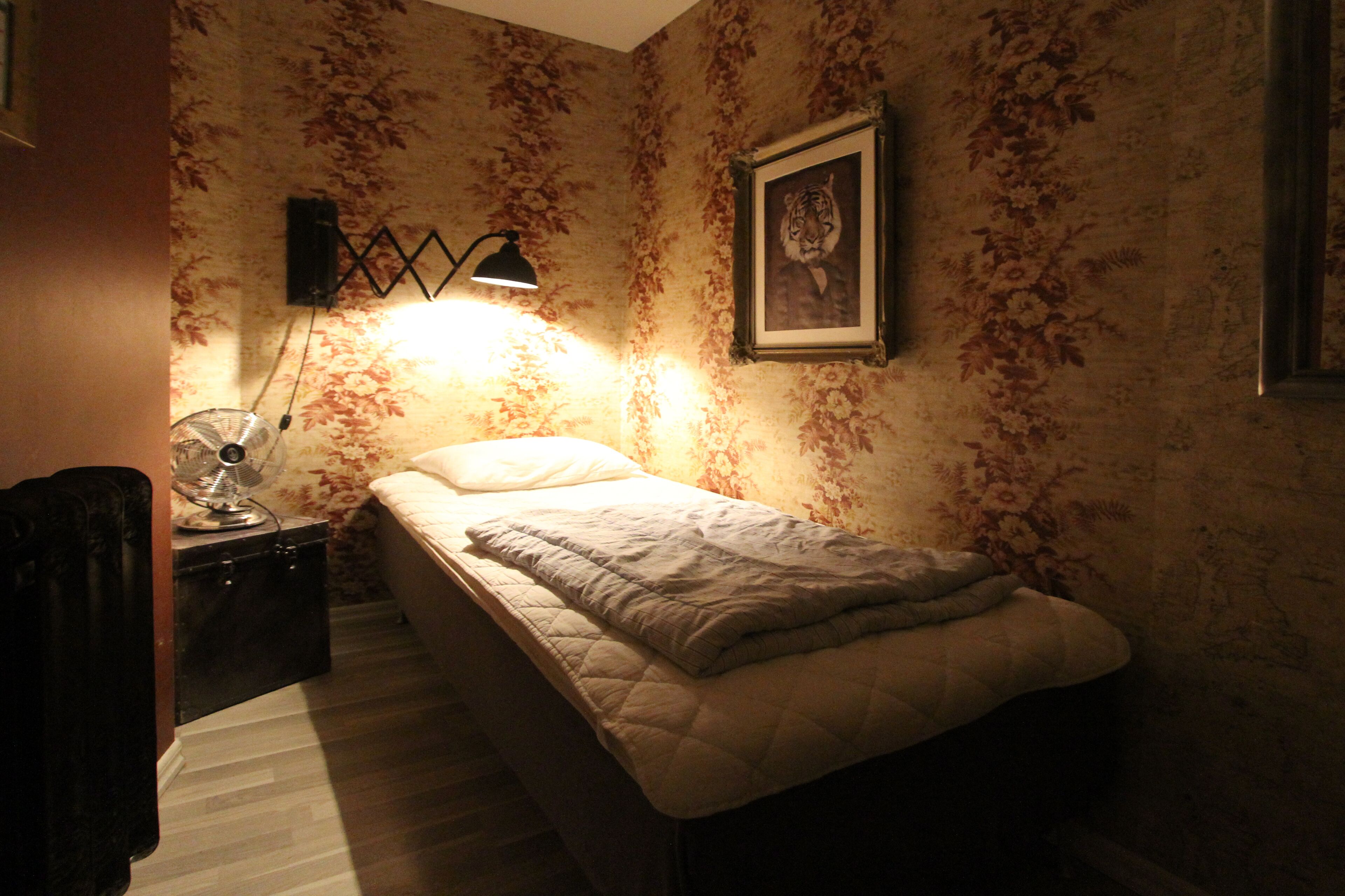A bedroom with a bed, a nightstand, a lamp, and a framed picture on the wall.