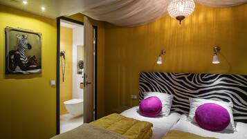 A hotel room with a zebra-themed headboard, a painting of a zebra, and a chandelier.