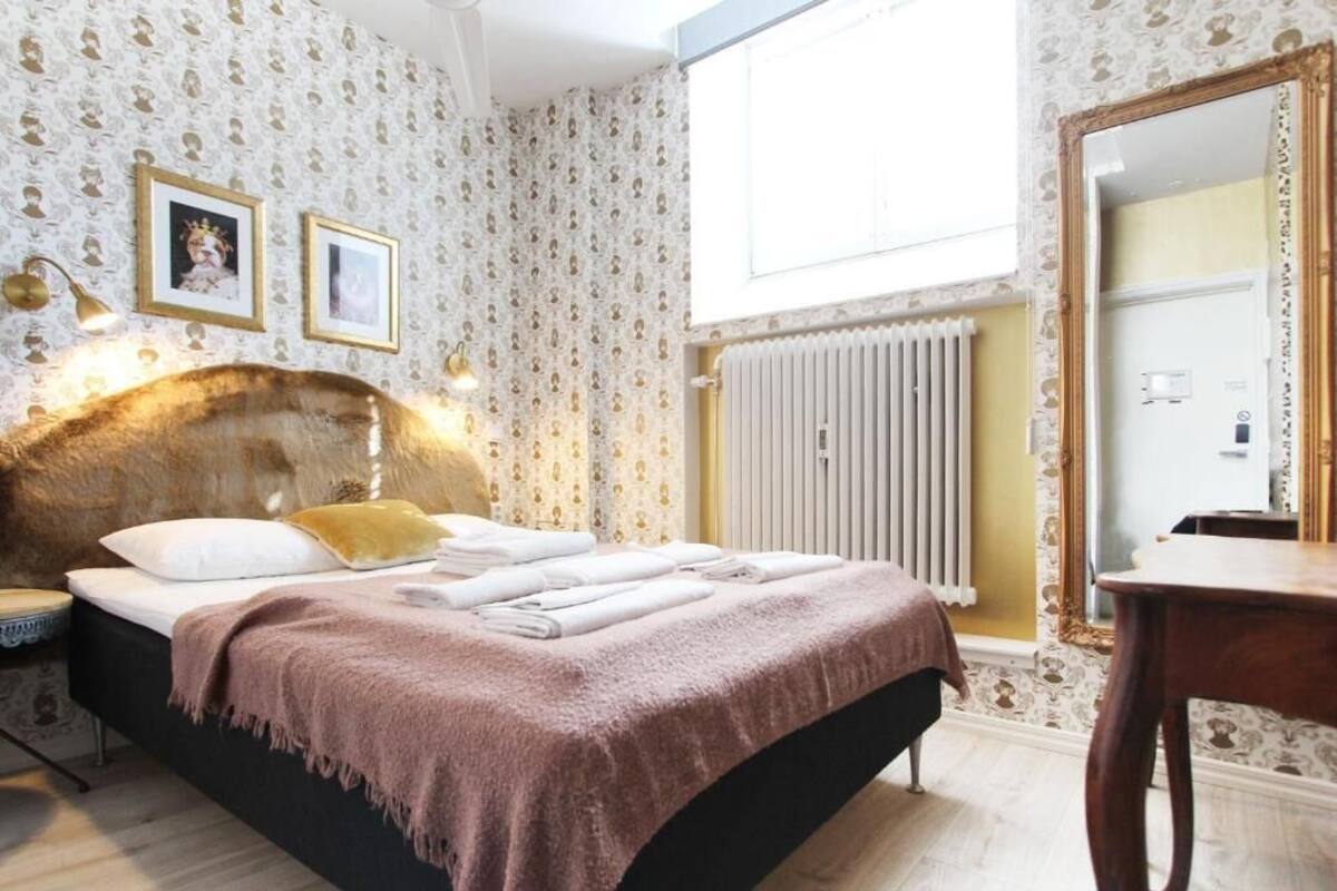 A neatly made bed with a headboard, a bedside table, and a mirror on the wall.