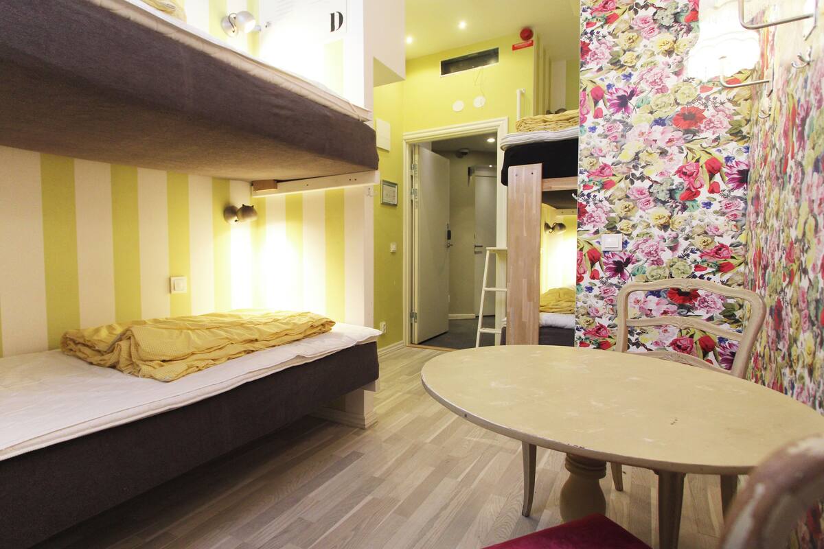 A small, compact room with a bunk bed, a round table, and a chair.