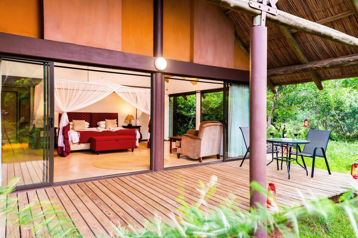 A modern villa with a large glass door leading to a bedroom with a red sofa and a canopy bed.