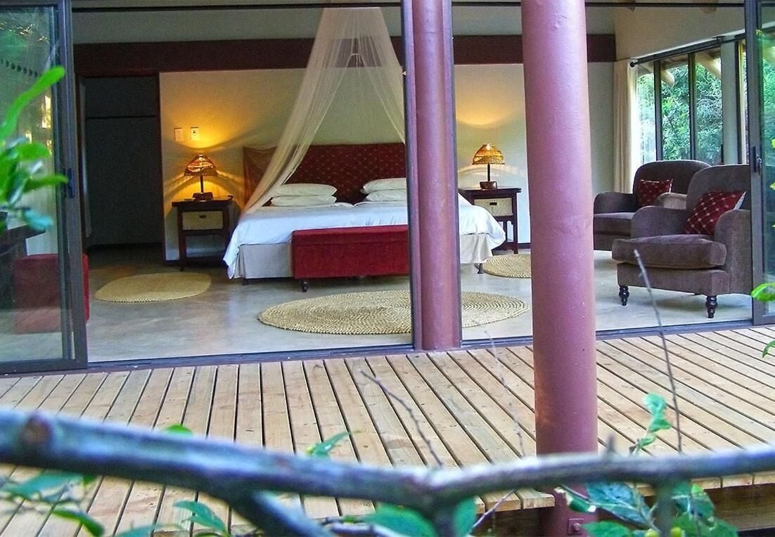 A bedroom with a bed, bedside tables, a chair, and a balcony.