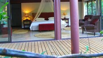 Ein Schlafzimmer mit Bett, Nachttischen, einem Sessel und einem Balkon.
