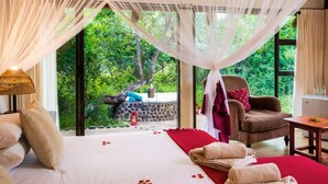 Une chambre à coucher avec un lit, une chaise, une table et une vue sur la verdure.