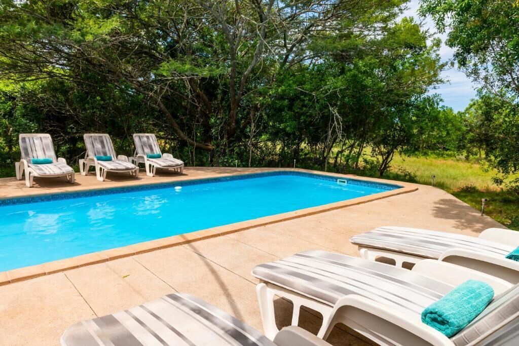 Piscina com espreguiçadeiras e um deck revestido de azulejos.