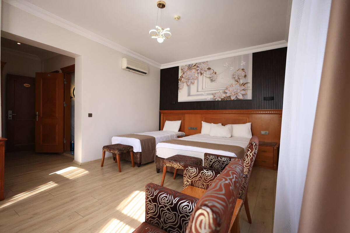 A hotel room with two beds, a wooden headboard, a large floral artwork on the wall, and a wooden floor.