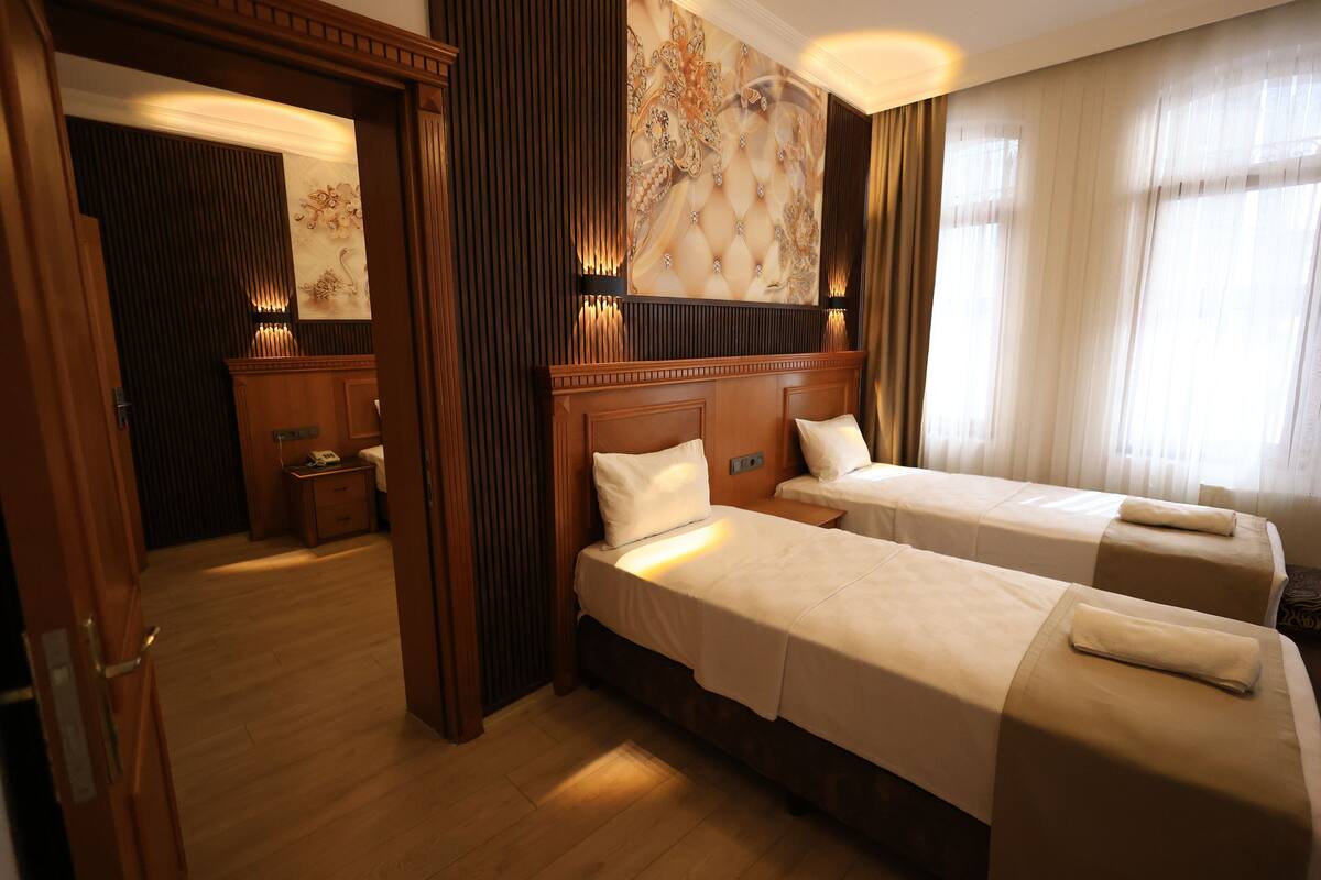 A hotel room with two beds, wooden headboards, a large decorative wall, and a mirror.